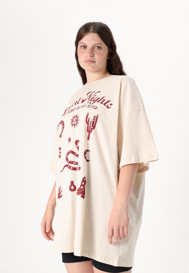 Beige oversize t-shirt met korte mouwen, met een rode graphic design van sterren, cactussen en westerse motieven op de voorkant.