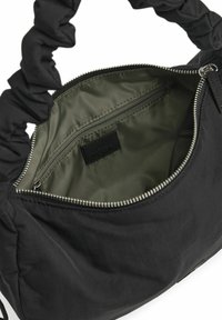 Sort stof håndtaske med en samlet håndtag og en olivengrøn foring. Har en indvendig lynlåslomme og metal lynlåslukning.