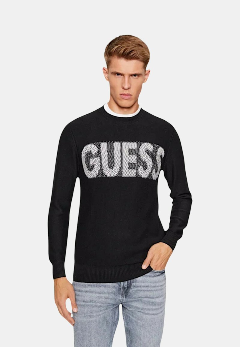 Maglione nero a maglia con un grande logo "GUESS" in bianco a contrasto. Collo a giro, polsini e orlo ribattuti. Vestibilità casual.