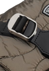 Nahaufnahme einer Metallspange, die einen schwarzen Riemen an einer glänzenden, olivgrünen gesteppte Stoffoberfläche befestigt.