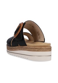 Black sandal with tan platform, featuring a round tan accent and an open back. Smooth leather upper and textured rubber sole with zigzag pattern.