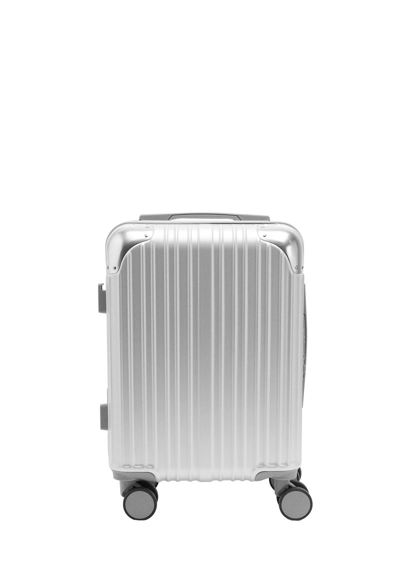 Srebrna walizka z twardą obudową, z pionowymi rowkami, wysuwanym uchwytem i czterema kółkami dla łatwości przemieszczania. Posiada zaokrąglone narożniki i solidną konstrukcję.