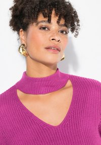 Maglione in maglia viola con colletto alto a coste e profondo scollo a V. Presenta dettagli a taglio sulle spalle, tessuto testurizzato e accenti lisci.