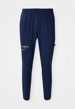 Navy blue athletic pants featuring an elastic waistband, tapered legs, and gold "PARIS" and Nike logos on the left leg.