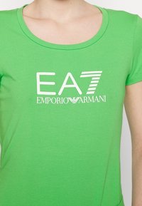 Zielony bawełniany t-shirt z okrągłym dekoltem i krótkimi rękawami, z białym logo EA7 Emporio Armani nadrukowanym na przodzie.