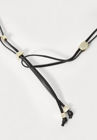 Colar de couro preto com três cordas, acentos geométricos dourados e extremidades ajustáveis com nós. Textura suave e design minimalista.