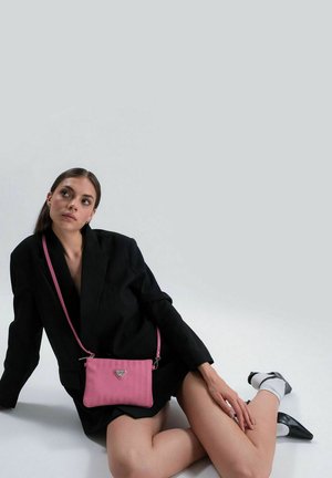 Rosa Leder-Umhängetasche mit strukturierter Oberfläche, silberner Logo-Hardware und verstellbarem Tragegurt, präsentiert vor einem neutralen Hintergrund.