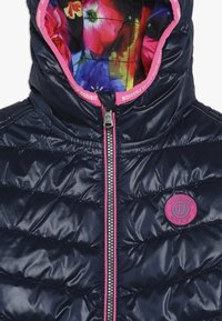 Námořnická modrá péřová bunda s lesklým povrchem. Má plné zipové zapínání, růžové akcenty a podšívku s vícebarevným květinovým vzorem.