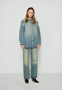 Set di camicia in denim e jeans a gamba larga, caratterizzato da un colore blu sbiadito, chiusura a bottoni frontale, maniche lunghe e una vestibilità rilassata con una leggera sfumatura.