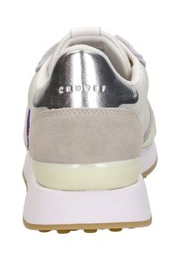 White sneaker with a metallic silver heel, grey suede accents, and a purple logo. Features a rubber sole and textured upper materials.