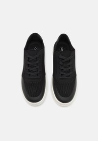 Baskets en mesh noir avec un bout lisse noir et une semelle en caoutchouc blanche. Comprend six œillets et une doublure intérieure douce.