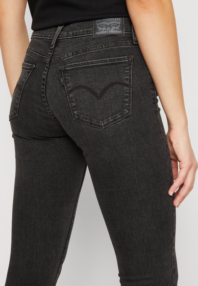 Jeans de mezclilla negra con un corte ajustado, que cuentan con costuras en dos tonos, bolsillos traseros con firma y un parche de cuero de la marca en la cintura.