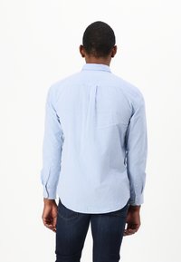 Camicia a maniche lunghe a quadri blu e bianchi con piega sul retro e orlo arrotondato. Il materiale sembra leggero e liscio.