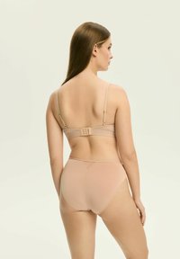 Beżowy zestaw biustonosza i majtek wykonany z gładkiego, elastycznego materiału. Biustonosz ma regulowane ramiączka oraz zapięcie na haftkę i oczko z tyłu.