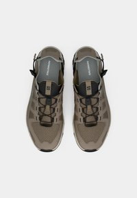 Ελαφριά μπεζ αθλητικά παπούτσια με ανώτερο μέρος από πλεκτό διακοσμημένο ύφασμα, μαύρες λεπτομέρειες, ελαστικά κορδόνια και επένδυση με μαξιλαράκι.