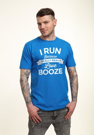 Blå bomulds T-shirt med hvid tekst: "JEG LØBER fordi jeg virkelig, virkelig elsker ØL." Korte ærmer og rund halsudskæring.