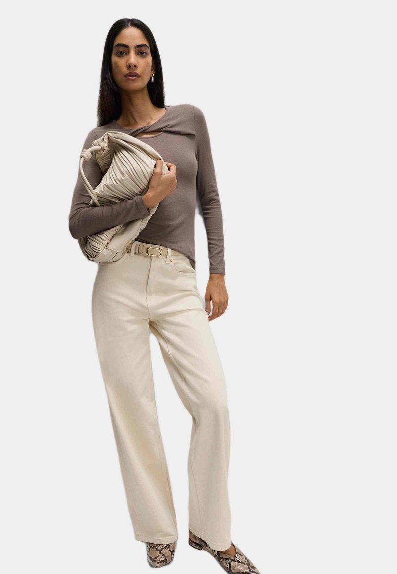 Bruine langemouwen top met een twistdetail, crèmekleurige wijde broek en een beige geplooide handtas. Textuur met slangenprint schoenen maken de look compleet.