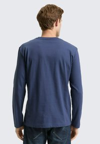 Granatowy długi rękaw t-shirt wykonany z bawełny, z okrągłym dekoltem i luźnym krojem. Widoczne szwy i gładka tekstura.