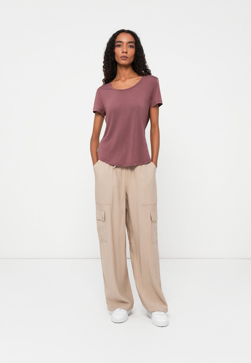Mauve krótki rękaw t-shirt z okrągłym dekoltem zestawiony z beżowymi spodniami cargo w szerokim kroju, posiadającymi boczne kieszenie i luźny fason.