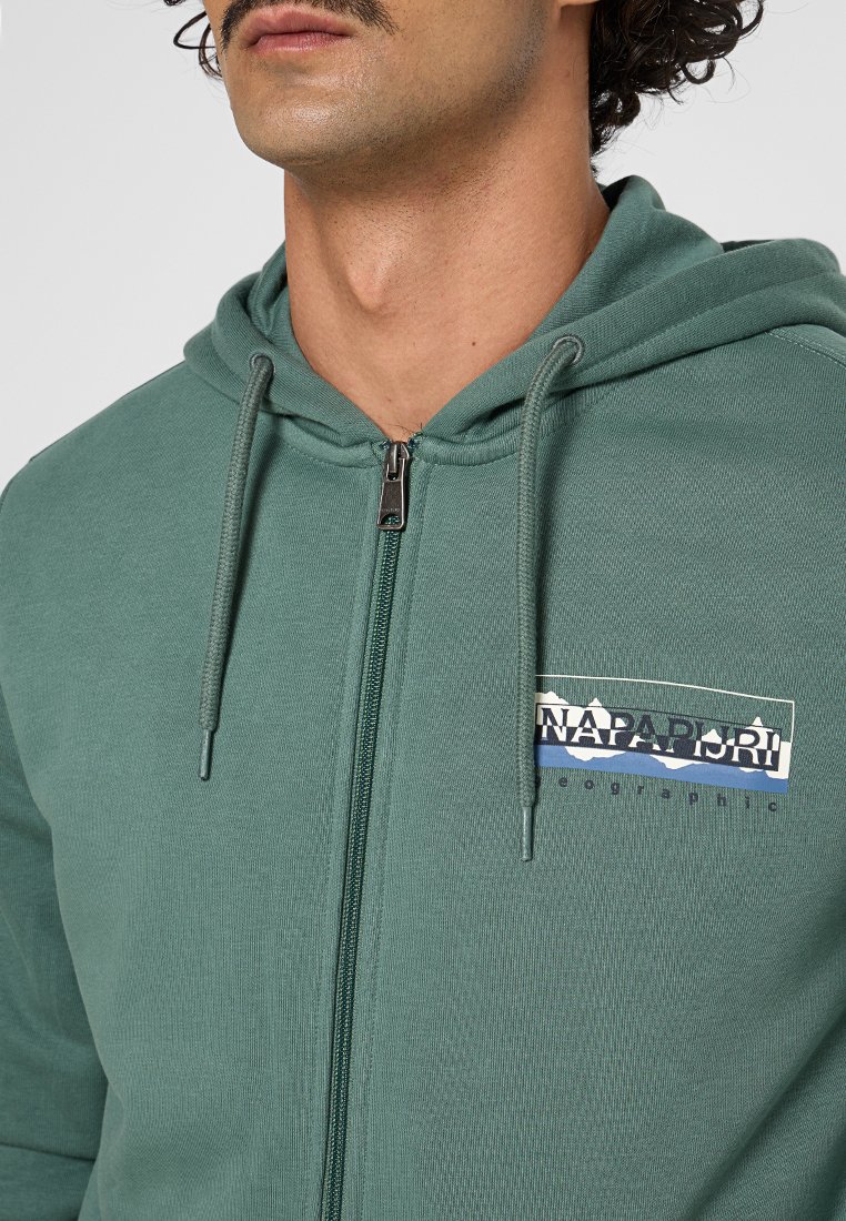 Zielona bluza z kapturem na zamek błyskawiczny i sznurkiem do ściągania, z graficznym logo na lewej piersi. Miękki materiał i teksturowana tkanina.