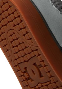 Suola di sneaker grigia con una texture in gomma a motivo marrone. Presenta un logo prominente e una presa testurizzata per una migliore aderenza.