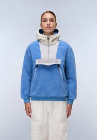 Blue fleece pullover with a muted gray panel and a high collar. Features a front zip, two zippers, and a branded chest accent.