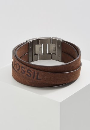 Bracelet en cuir marron à enfiler avec fermoir en métal, présentant le logo "FOSSIL" embossé sur la bande.