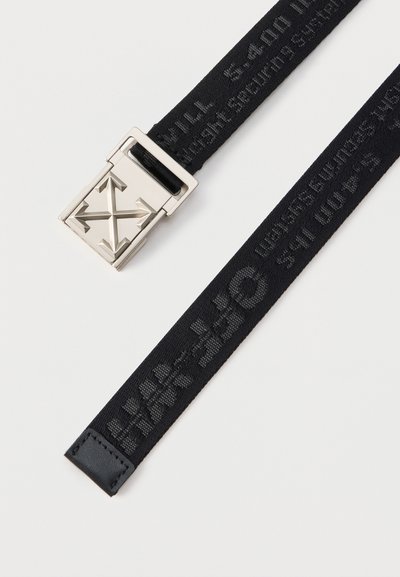 Μαύρη υφασμάτινη ζώνη με κείμενο σε σχέδιο και τετράγωνη ασημένια αγκράφα με τέσσερα βέλη που δείχνουν προς τα έξω σε σχήμα σταυρού.