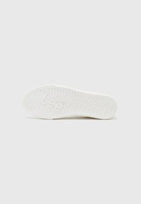 White rubber shoe sole with a wavy texture, featuring a logo and multiple ridges for grip. Simple, flat design without accents.