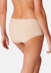 Beige hipster-alusvaatteet, joissa on saumaton muotoilu, pehmeä rakenne ja yksinkertainen vyötärönauha. Sileä pinta ilman näkyviä saumoja tai koristeita.