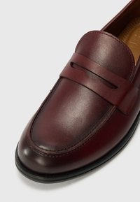 Burgundia nahast loafer ümmarguse varbaga, millel on horisontaalne rihm ülaosas ja peened õmblused. Must kummist tald.