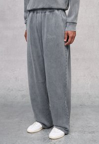 Zachte, grijze sweatpants met een losse pasvorm, voorzien van een elastische tailleband, zijzakken en subtiele geborduurde logo-details op het been.