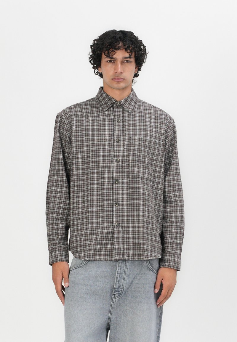 Bruin en beige geruit overhemd met een kraag, lange mouwen en een borstzak, gecombineerd met lichtgrijze denim jeans.