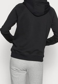 Zwarte hoodie met raglanmouwen, geribde boorden en zoom, gecombineerd met grijze sweatpants. Gladde stof en casual pasvorm.