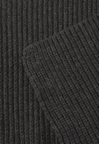 Dark gray ribbed fabric displaying a textured surface with vertical lines. Threads are soft and slightly fuzzy, showcasing a close-knit structure.