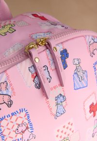 Rózsaszín hátizsák, amely rajzfilm kutyák mintáját és színes anyagokat tartalmaz, arany cipzárokkal és rózsaszín gumifüllel.