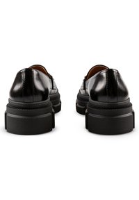 Zwarte leren schoenen met een ronde neus en een dikke, gestructureerde zwarte rubberen zool. Gladde afwerking met subtiele stiksels.