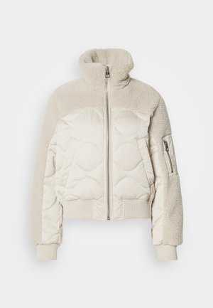 Padded cream jacket with a high collar, textured sherpa accents on shoulders, ribbed cuffs, and a side zippered pocket.