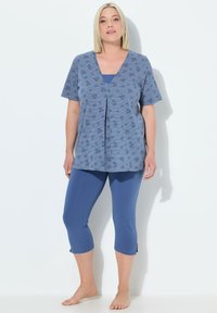 Top de algodón azul con mangas cortas, con escote en V y detalle de pliegue, combinado con leggings capri a juego. Textura suave, corte relajado.