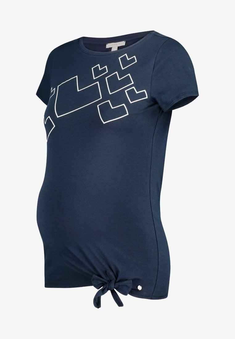Laivansinisen äitiys T-paitojen, lyhyet hihat, jossa on valkoinen geometrinen painatus ja sidottu yksityiskohta alareunassa vasemmalla. Pehmeä, joustava kangas.