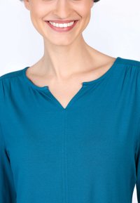 Türkise Bluse mit V-Ausschnitt, weichem Stoff und dezenten Fältchen an den Schultern. Verfügt über saubere Nahtdetails und einen entspannten Schnitt.