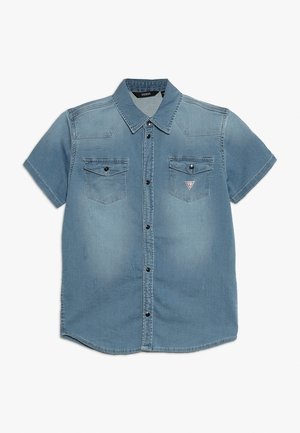 Lyseblå denimskjorte med korte ærmer, krave, frontknapper og to brystlommer, hvoraf den ene har et lille trekantet Guess-logo.