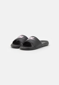 Sandales noires à glissière avec un design à bout ouvert, dotées d'une sangle texturée et d'un logo rose sur le dessus. Fabriquées en matériau synthétique avec une semelle plate.