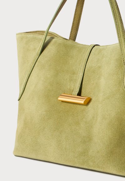 Geantă tote din suede verde, cu un accent auriu alungit pe partea din față, având mânere duale și o textură moale. Design simetric.