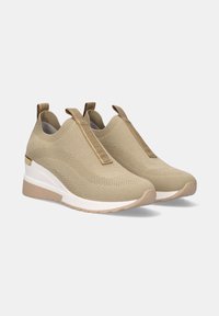 Zapatos beiges tipo slip-on con una parte superior de punto transpirable, que cuentan con un tacón cuña, un patrón texturizado y una cinta elástica para un ajuste seguro. Suela blanca.