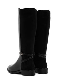 Botas negras hasta la rodilla que combinan cuero liso y suave ante, con un diseño elegante y un acento de cinta cerca del tobillo.