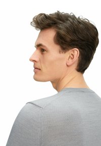 Grauer, taillierter Pullover mit Rundhalsausschnitt und gerippter Textur, der die Schulternaht zeigt und eine glatte Oberfläche hat, getragen von einer Person, die von der Seite betrachtet wird.