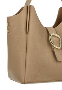Bolso de mano de cuero beige con superficie texturizada, detalle ovalado de metal dorado y forma estructurada con botones decorativos.