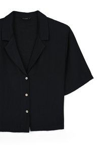 Chemise noire à manches courtes avec col, à coupe droite, dotée de trois boutons sur le devant et d'un tissu texturé.