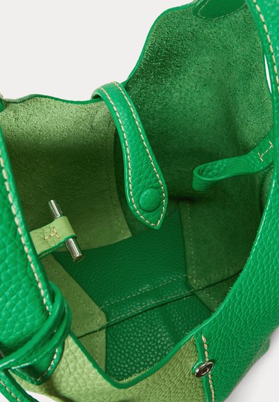 Open groene leren handtas met zicht op de gestructureerde binnenkant, gestikte schouderriem met drukknop en zilveren draaisluiting.